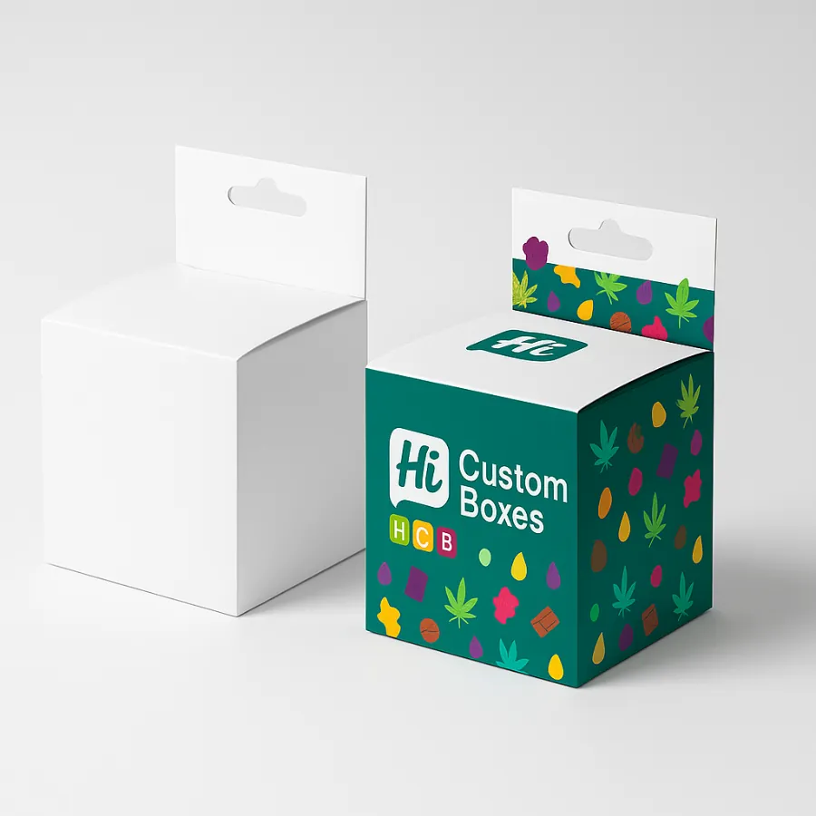 Two small cube boxes for edibles packaging with a hang tab- one plain white and one in a colourful leaf and candy pattern on a teal background- class=