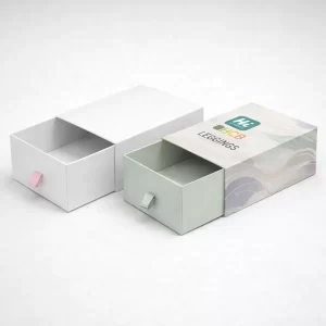 Two slide-out drawer boxes with ribbon pulls, one plain white and one with patterned sleeves.