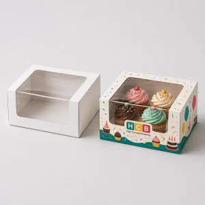 Two square boxes with top window cutouts showing a decorated birthday cake inside one.