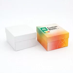 Two square rigid gift boxes, one plain white and one with vibrant sunset-coloured gradient branding.