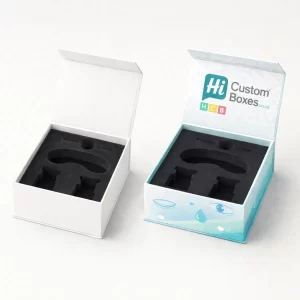 Two flip-top rigid boxes with black foam inserts, one plain white and one featuring light blue branding.