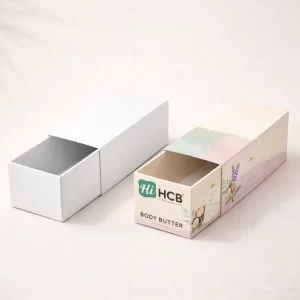 Two open cardboard mailer boxes, one plain brown and one featuring custom pink body butter branding.