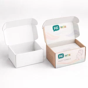 Two open cardboard mailing boxes, one plain white and one printed with a colourful towel brand.