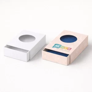Two sliding drawer boxes with circular window cut-outs, one plain white and one patterned pink.