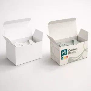 wo open tuck-top boxes side-by-side, showcasing internal branding and a pale green garment inside.