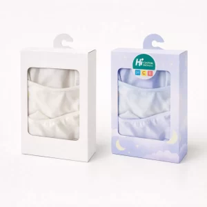 Two hanging retail boxes with windows showing folded white and light blue pyjama sets inside.