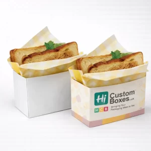 Two open-top square cardboard containers holding toasted bread slices wrapped in yellow checkered paper.