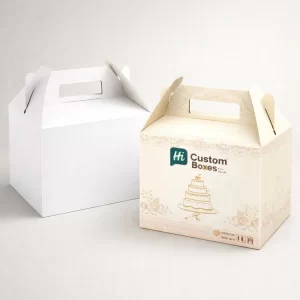 Gable-style wedding cake boxes with handles, displaying a cream-coloured bespoke design alongside a minimalist plain white version.