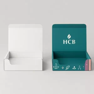 Open display box mockup, one plain white and one custom printed with teal and pastel candle-themed design, showing the HCB logo inside the lid.