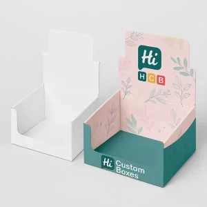 Open counter display box mockup shown in plain white on the left and branded design on the right with pink and teal floral patterns and "Hi HCB Custom Boxes" logo.