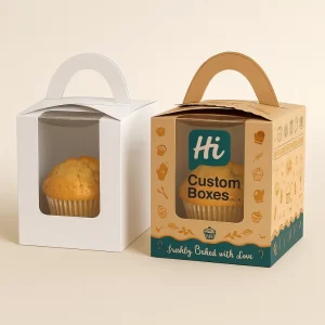 Two single muffin packaging boxes with handles and a clear window- one in white and one in custom-printed kraft paper- holding a single baked muffin