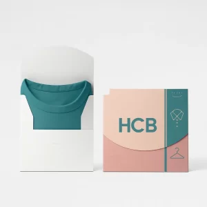 Shirt packaging folder boxes- one plain white holding a teal folded shirt and the other branded with pink and teal -HCB- design featuring shirt icons and hanger graphics