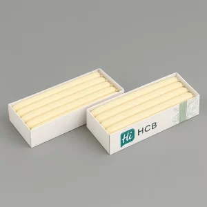 Two rectangular white boxes displaying rows of six long, cream-coloured taper candles.