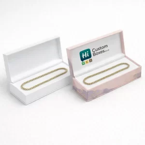 Elegant white and pink hinged boxes displaying gold beaded anklets on soft white padded inserts
