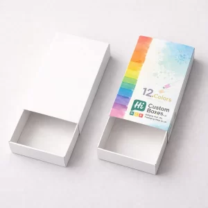 Two sliding drawer-style pencil boxes; one is plain white and the other shows a 12-colour rainbow and paint effect.