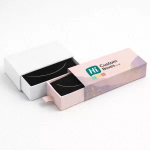 Two premium drawer-style jewellery boxes in white and lilac- featuring gold chain anklets on velvet