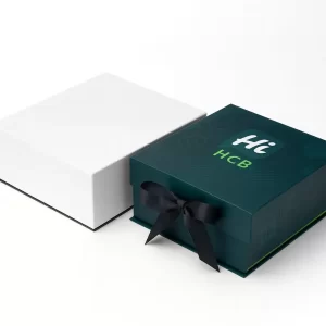 Custom collapsible magnetic box wrapped with a black satin bow- A plain white box is positioned next to a dark teal box with a custom logo print on the lid